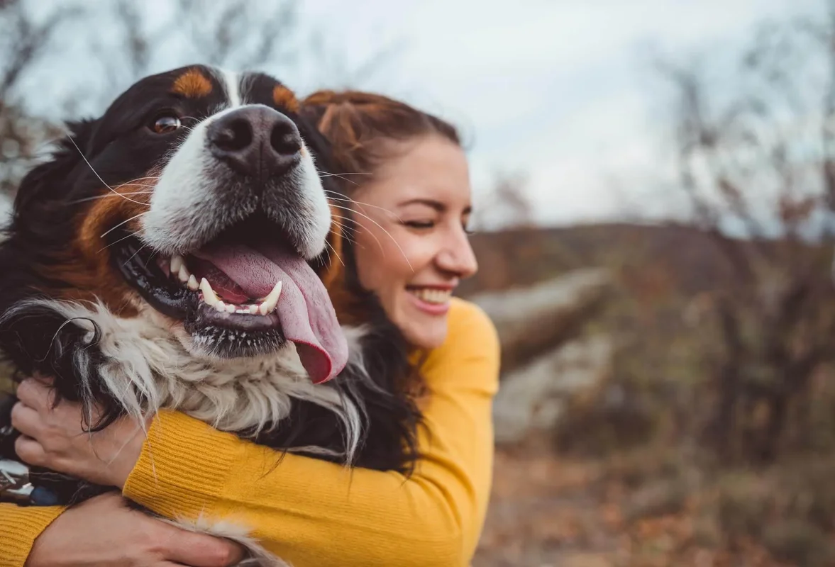 Dog sitter tenant un chien joyeux lors d'une promenade en extérieur durant la garde.